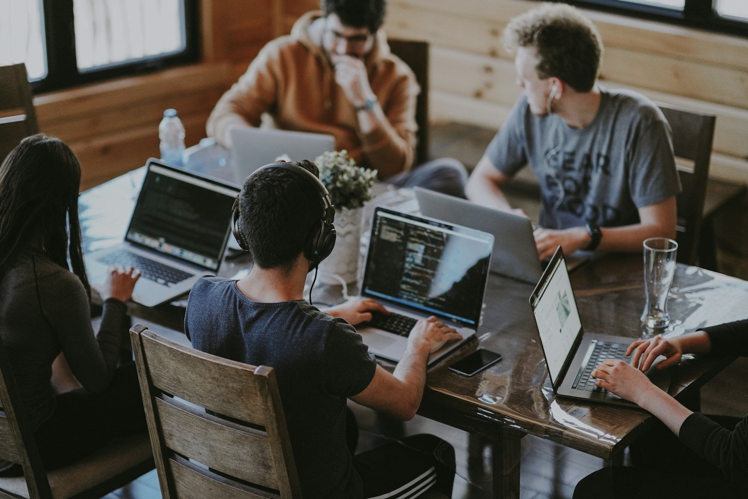 Personas conversando y trabajando alrededor de una mesa con computadores