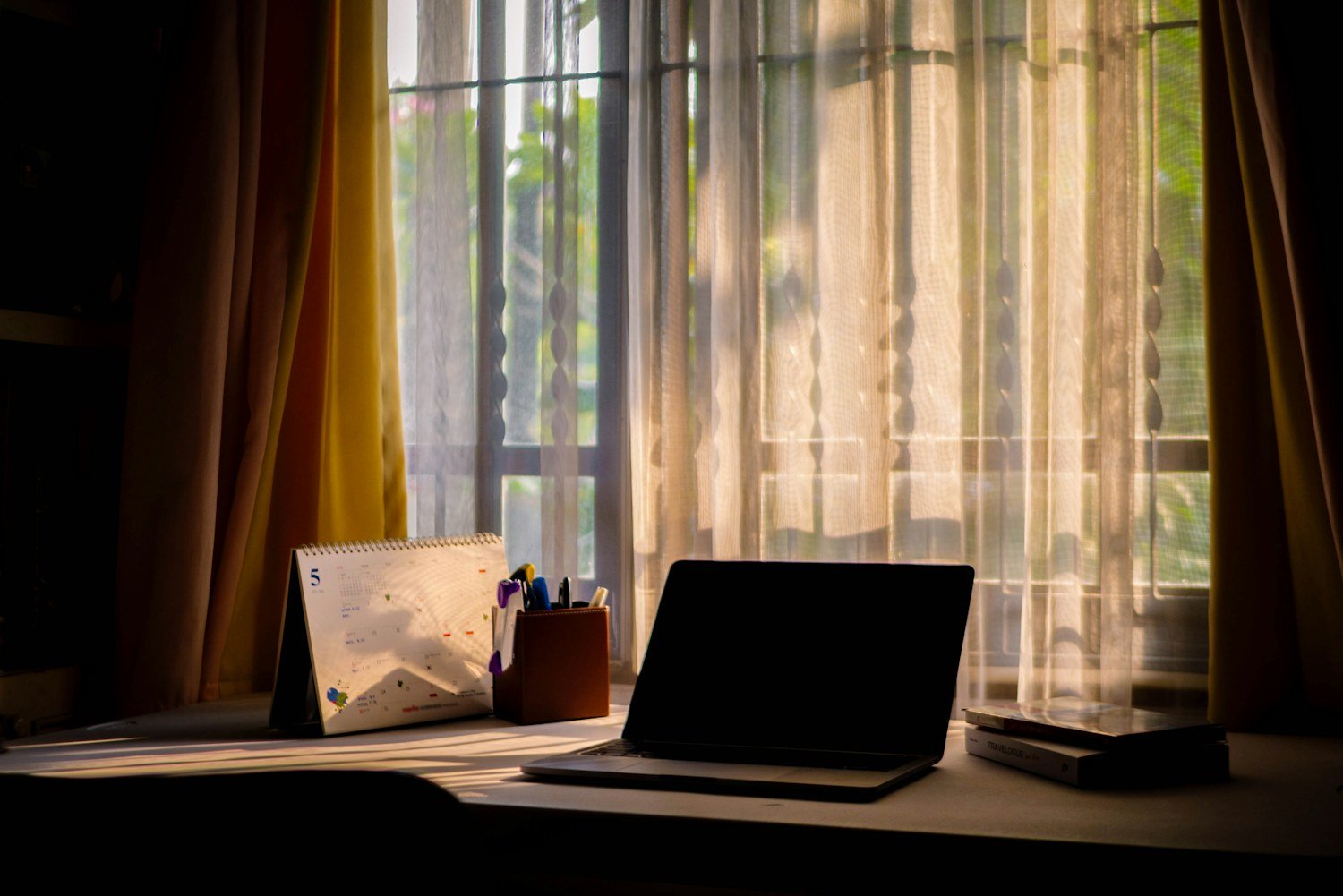 Computador portátil en un escritorio junto a una ventana con luz natural